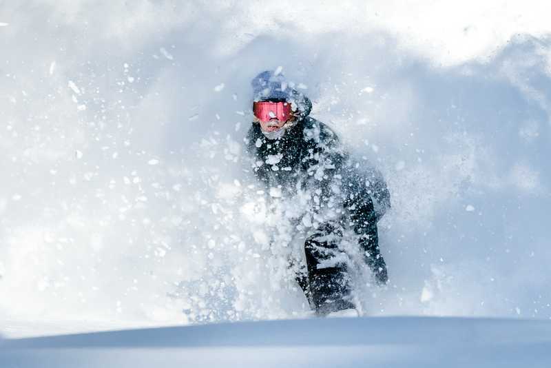 Head on shot of a snowboarder with powder flying up