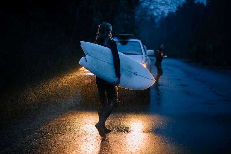 Woman holding a surfboard in the rain