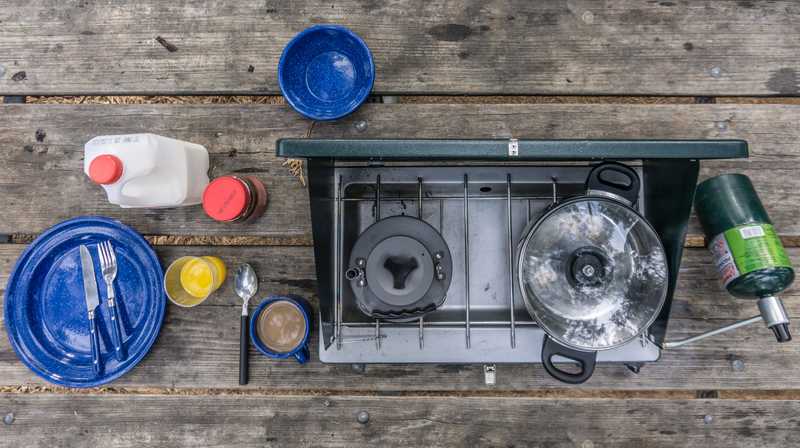 Overhead shot of a camp stove and some utensils on a picnic table
